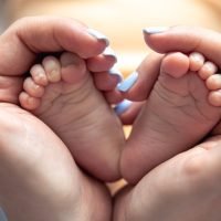 mom-holds-legs-newborn-baby-her-hands (1) (1) (1)
